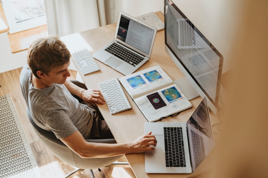 personne assise devant trois écrans d'ordinateur